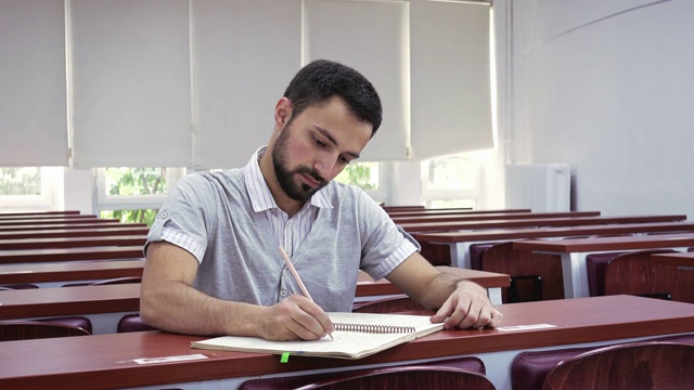 年轻的学生在空荡荡的讲堂里记着笔记，独自在空荡荡的教室里学习视频素材