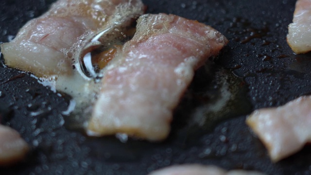 熏肉和鸡蛋是在煎锅里煮的。热煎锅里的培根和鸡蛋，特写。窗户的自然光视频素材