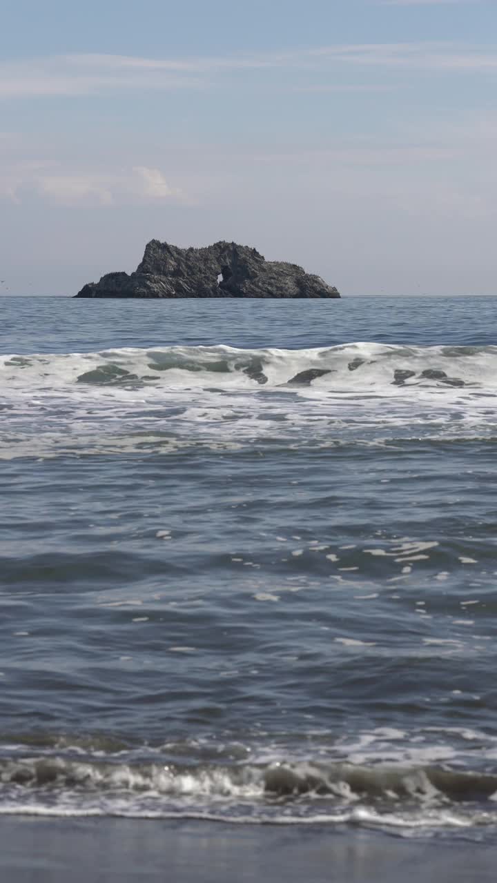 美丽的风景海浪在太平洋和岩石岛在地平线上。垂直视频。视频素材