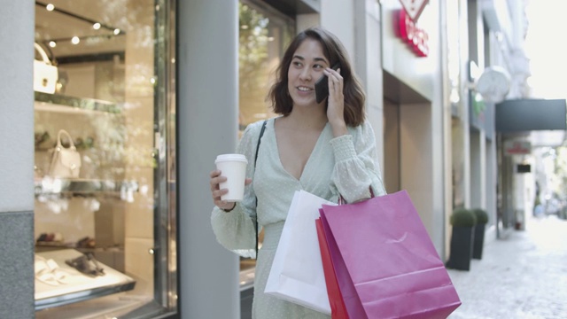 一个拉丁妇女一边打电话一边看商店橱窗视频素材