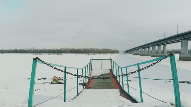 在冰雪覆盖的河面上，五颜六色的生锈码头视频素材