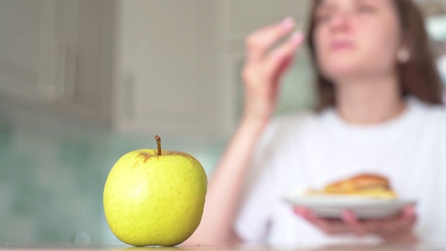 不健康的食物选择。营养不良和暴饮暴食。女人吃芝士汉堡和薯条而不吃苹果视频素材