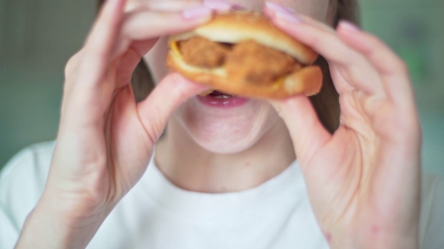 快吃午饭。一个女人咬一个素食汉堡特写。不健康的快餐视频素材