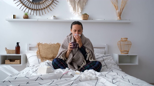 生病的女人在家里喝热茶和咳嗽视频素材