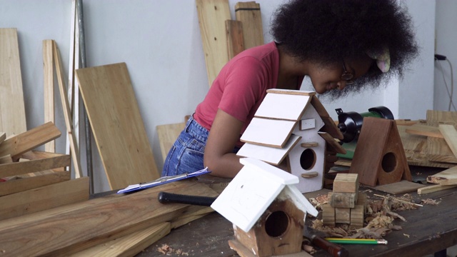 年轻的非洲裔美国女孩开始建造鸟屋作为一种创造性的休闲爱好，呆在你的桌子上在一个家庭木匠假日活动视频素材