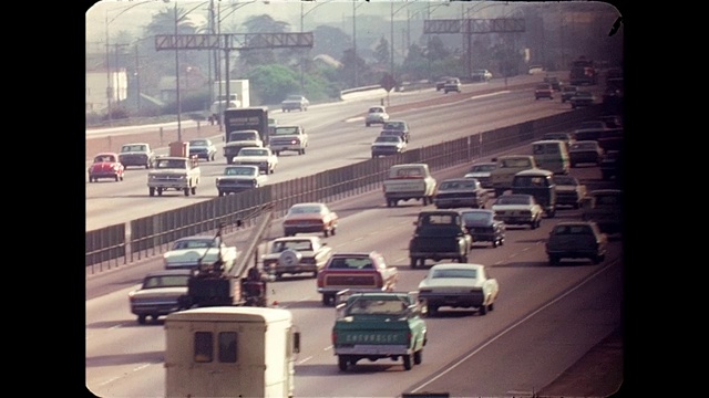 长镜头PAN在1970年代早期的高速公路交通高峰时间在市中心附近从天桥上看到视频素材