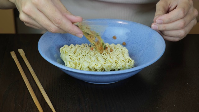 女人煮方便面鸡蛋面，加入蔬菜，香料和开水视频素材