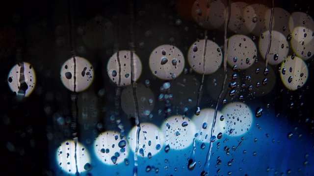 晚上雨点打在窗户上，散景灯在背景，晚上下大雨视频素材