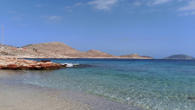 这是爱琴海在哈尔基(Chalki)岛的夏天，在清澈湛蓝的海水上，锈迹斑斑的岩石山的映衬下拍摄的照片视频素材