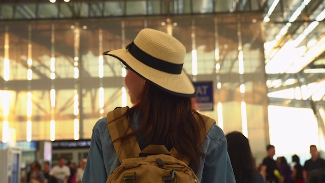 一个漫不经心的年轻女子在候机楼的门口走着。年轻妇女独自乘飞机旅行。视频素材