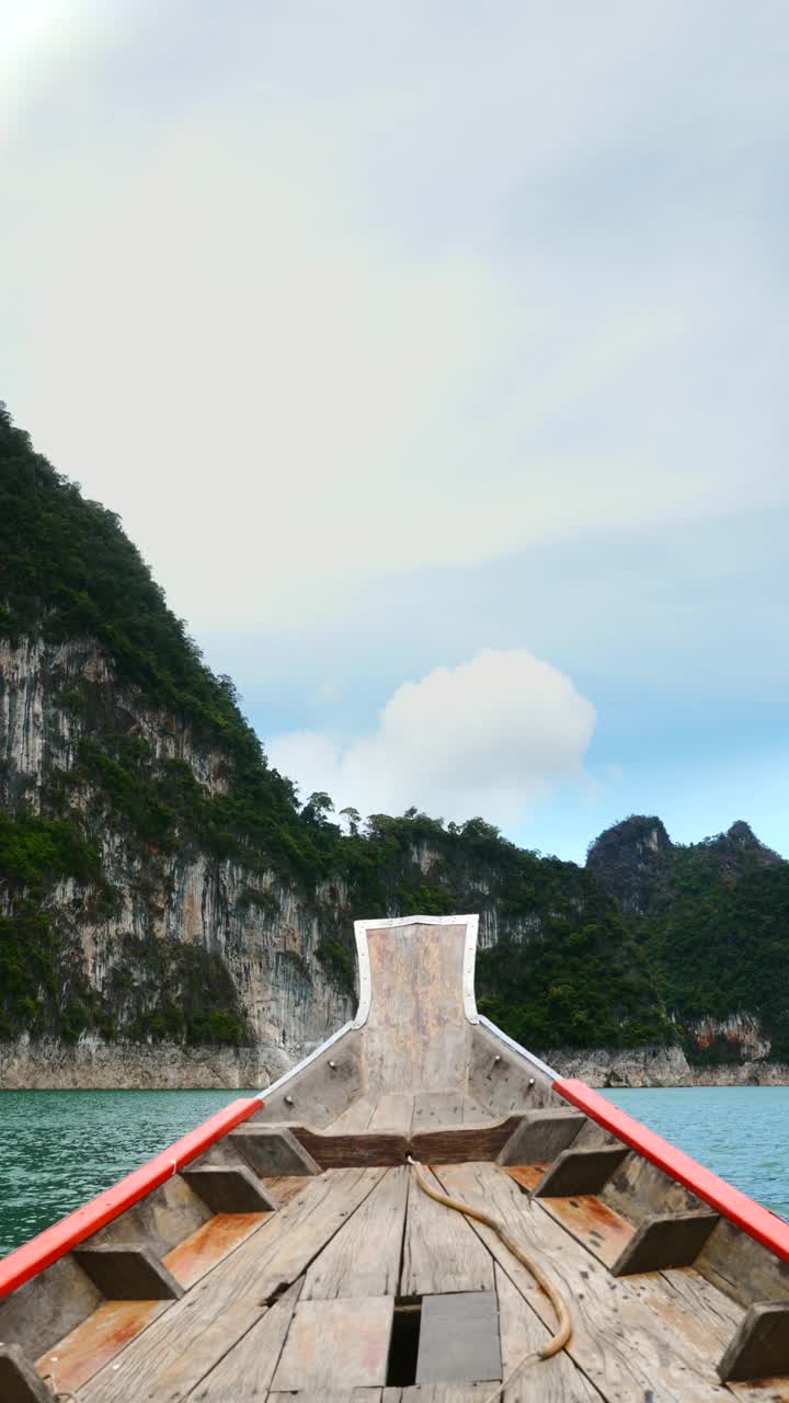 在石灰石悬崖附近的木材长尾船上的蓝色湖上旅行的垂直视频视频素材