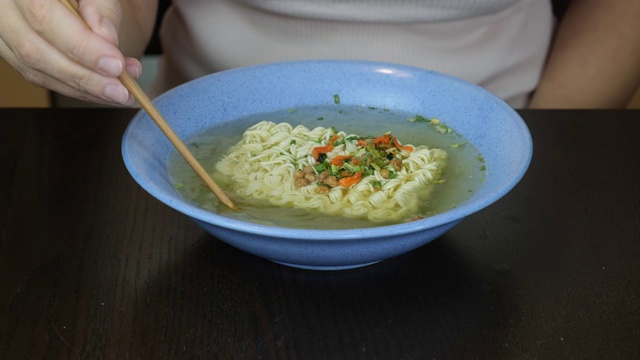 女人煮方便面鸡蛋面，加入蔬菜，香料和开水视频素材