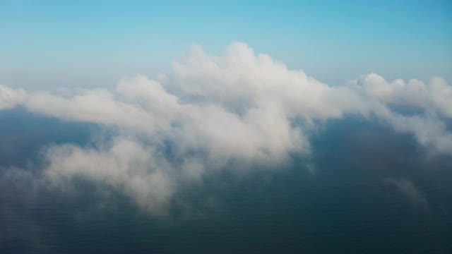 移动白云的风景鸟瞰图。无人机穿过前方蓬松的云，在蔚蓝的天空中高飞。太阳被云遮住了。准备好你的文本和设计素材视频素材