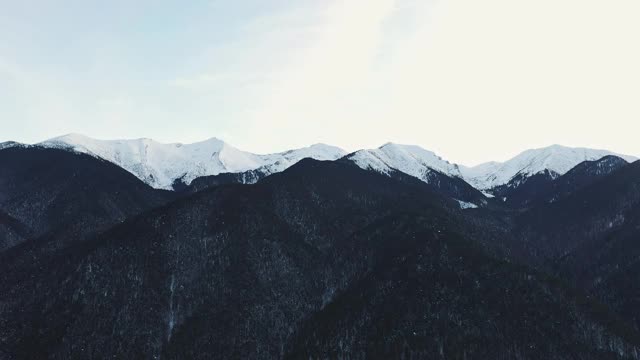 皮林，全景雪山山峰通过升起的薄雾在清晨鸟瞰一天的黎明。冬天美丽的山脉。漂浮的雾在山上日出。旅游业。旅行视频素材