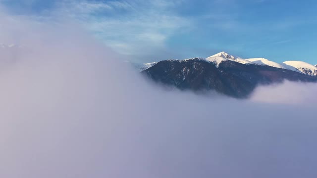 皮林，全景雪山山峰通过升起的薄雾在清晨鸟瞰一天的黎明。冬天美丽的山脉。漂浮的雾在山上日出。旅游业。旅行视频素材