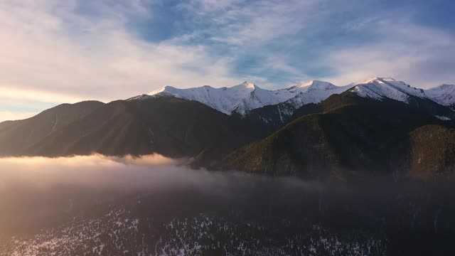 皮林，全景雪山山峰通过升起的薄雾在清晨鸟瞰一天的黎明。冬天美丽的山脉。漂浮的雾在山上日出。旅游业。旅行视频素材