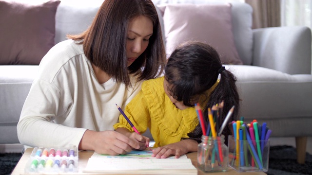 妈妈在家里的客厅教小女孩画画视频素材