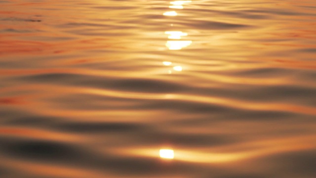 海面与小波浪的背景日出的太阳。太阳升起海面，太阳的路径在水上滑行缓慢的运动。金色的海洋全景视频素材