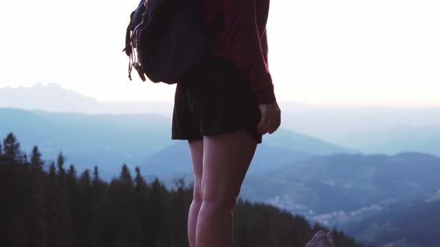 年轻的红发女游客在日落日站在高山顶上用智能手机自拍，背景是巨大的山湖。放松。镜头光晕。旅行。生活方式视频素材