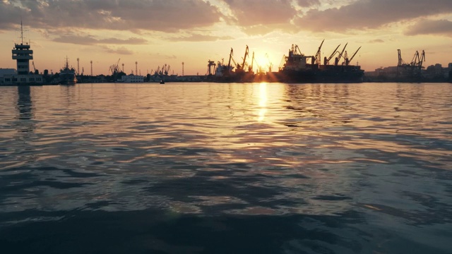 海上城市港口。海面平静的摇摆。一群海鸟、海鸥，在明亮的橙色夕阳背景下，盘旋在船只和起重机上视频素材