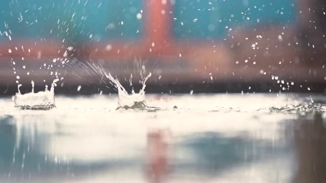 雨滴落在地面模糊的背景上，美丽抽象的季节壁纸屏幕，雨的飞溅水是美丽的，特写泡泡和飞溅运动和落在地面上视频素材