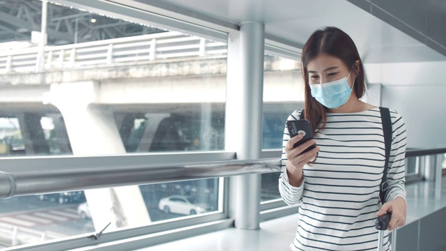 一名年轻女子戴着口罩在机场候机厅使用智能手机视频素材