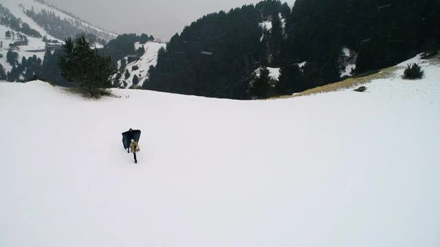 情侣在雪下拥抱，周围是白雪和群山。美丽的雪景与山脉遍布地平线- 4K视频素材