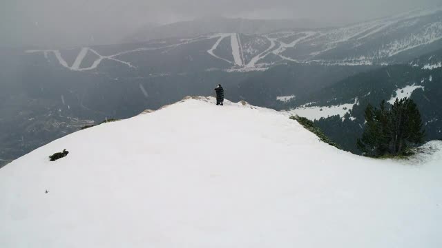 夫妻雪下，在悬崖边看地平线，四周群山环绕——4K视频素材