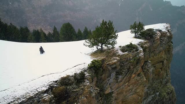 一对夫妇从悬崖边回来，四周群山环绕，在4K雪下视频素材