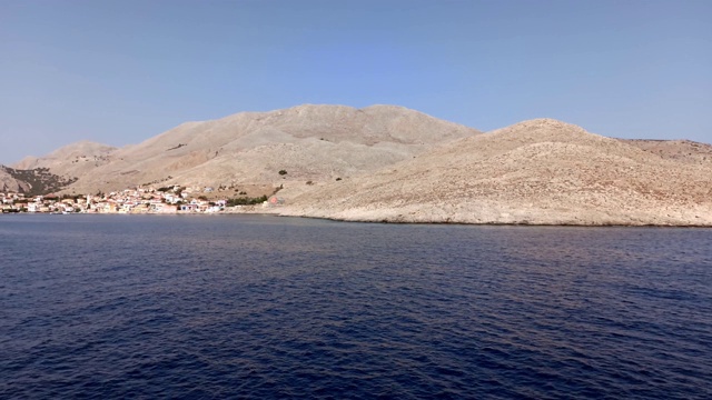 一艘船缓缓地驶近安普里奥港，在爱琴海十二岛岛的一个多山岛屿上的哈尔基/查尔基岛，距离罗得斯岛以西约6公里(4英里)视频素材