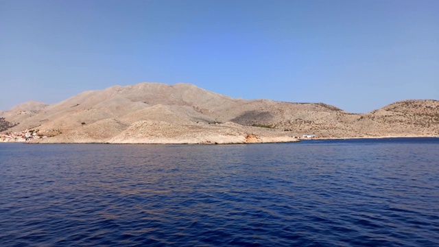 一艘船缓缓地驶近安普里奥港，在爱琴海十二岛岛的一个多山岛屿上的哈尔基/查尔基岛，距离罗得斯岛以西约6公里(4英里)视频素材