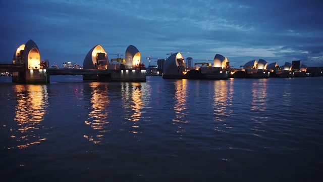 在英国伦敦，泰晤士河屏障的灯光在夜间倒映在水面上的全景图。夜景。——广角镜头视频素材