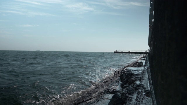 涌潮。海浪拍打着岩石。波浪在岩石上翻滚。阳光灿烂的夏日，海浪拍打着石头视频素材