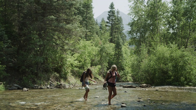 远处的少女徒步穿越森林小溪/ Tibble Fork，犹他州，美国的广角镜头视频素材