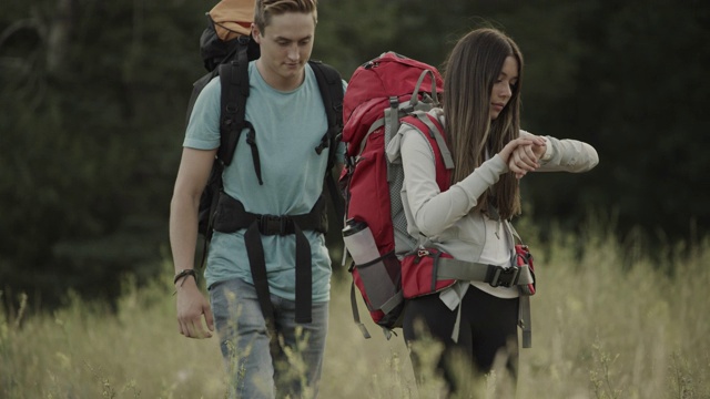 一对青少年情侣在野外徒步旅行，然后女孩对着智能手表说话/ Tibble Fork，美国犹他州视频素材