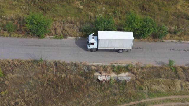 航拍的卡车与货物拖车驾驶在道路上运输货物。在乡村公路上飞驰的运送卡车。工业汽车驶向目的地。物流的概念。视频素材