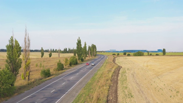 空中拍摄的电动汽车行驶在乡村道路上。新型现代车辆在高速公路上快速行驶。飞过高速公路上的汽车。农村环境中的交通。慢镜头视频素材