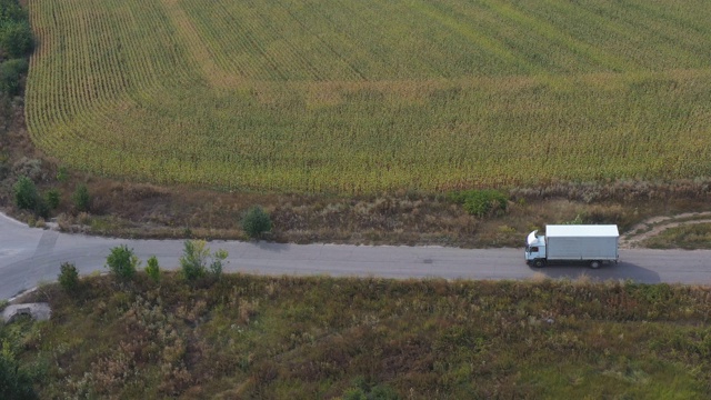 航拍的卡车与货物拖车驾驶在道路上运输货物。飞过在乡村公路上行驶的运货车。风景优美的自然场景。物流的概念。侧视图视频素材