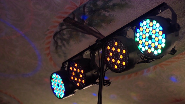 彩色闪烁的射灯悬挂在天花板和照亮空间，四个霓虹灯闪烁在迪斯科派对，婚礼或生日庆祝，或在夜总会娱乐。灯光设备及效果，灯光反射概念视频素材