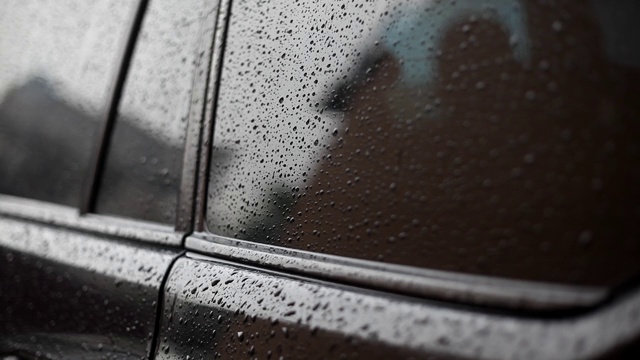 一位妇女用手掌擦湿了车窗。雨点落在车身和玻璃上。水滴顺着机器本体流下。雨滴落在黑色的汽车上。雨天。视频素材