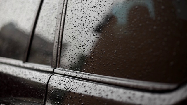 雨点落在车身和玻璃上。水滴顺着机器本体流下。雨滴落在黑色的汽车上。雨天。视频素材