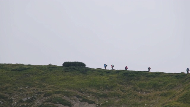 一群背着徒步背包的游客攀登山脉。远处的观点视频素材