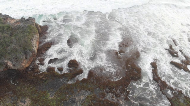 岩石海滩海浪白色泡沫水溅击中岩石无人机视频素材