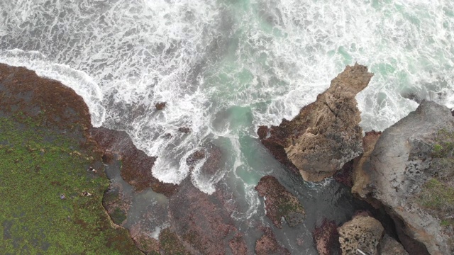 岩石海滩海浪无人机水溅击中岩石悬崖，泡沫白色的水视频素材