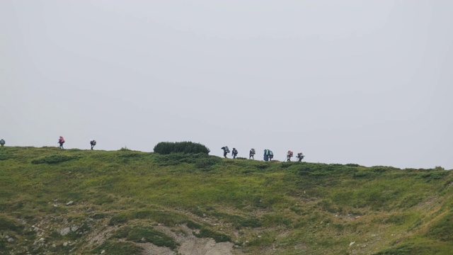 一群背着徒步背包的游客攀登山脉。远处的观点视频素材