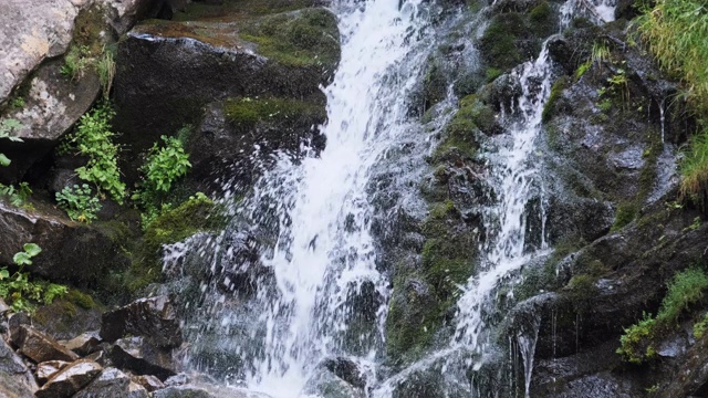 野生山瀑布。快速下落的水击中石头。慢动作视频素材