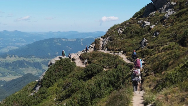 一群背着背包的游客和孩子们沿着山上的石头小径下山视频素材