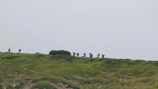 一群背着徒步背包的游客攀登山脉。远处的观点视频素材