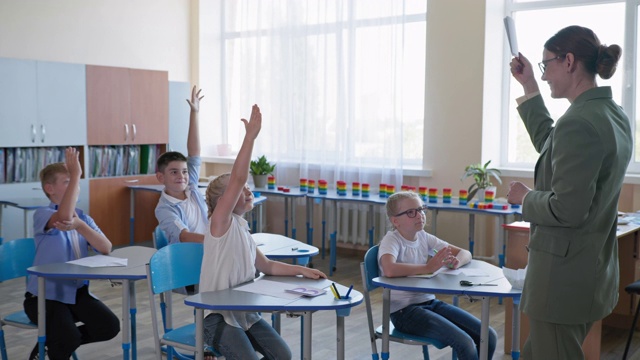 小学课堂上的多元聪明的孩子们听着老师讲课，学生们每个人都举手知道正确的答案视频素材