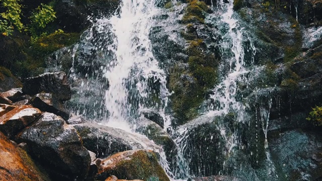 野生山瀑布。快速下落的水击中石头。慢动作视频素材